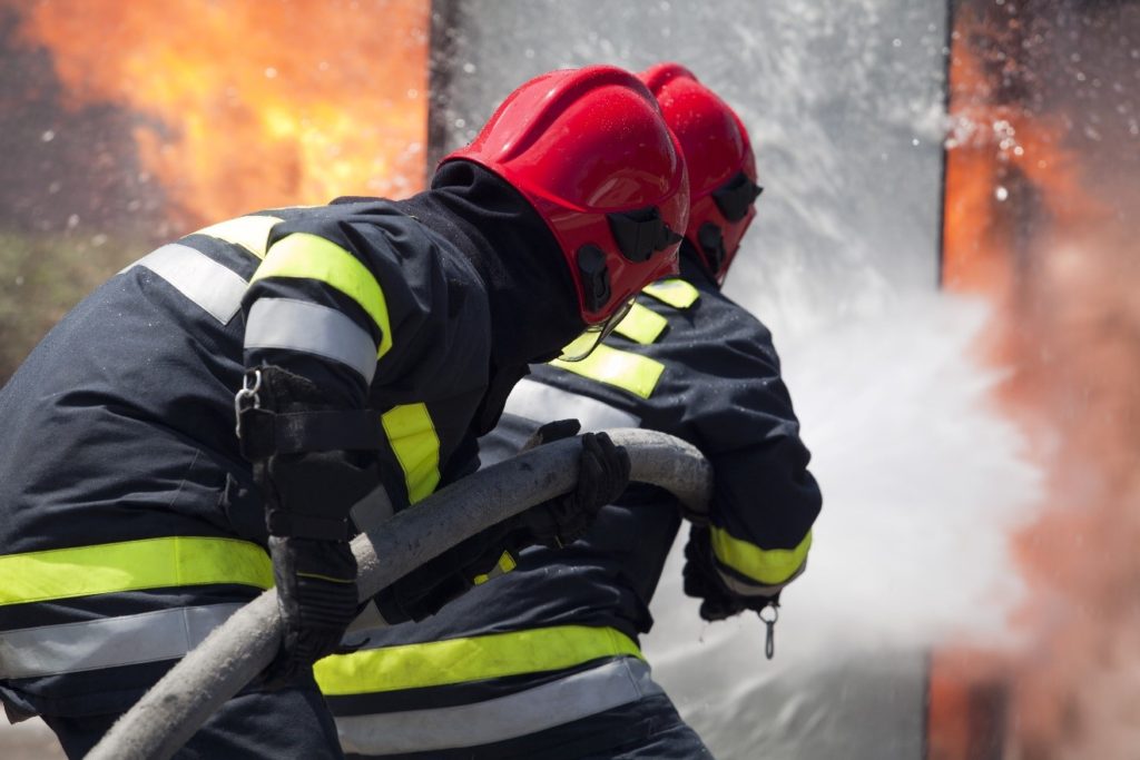 firefighters using a hose to put out a fire